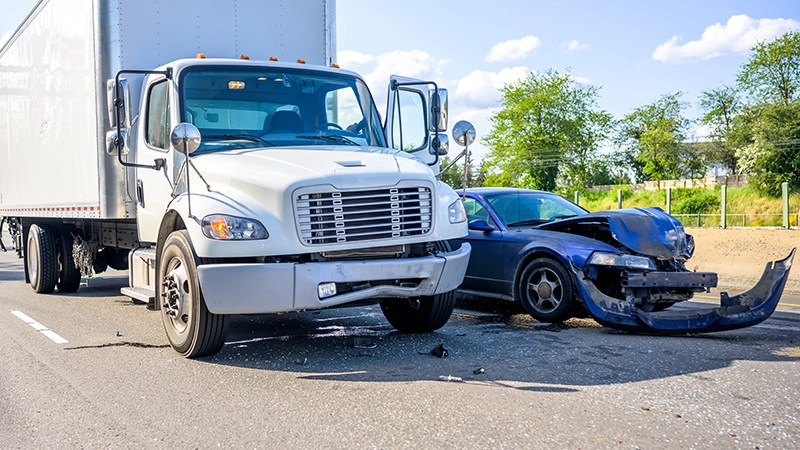Collision of a semi truck with box trailer a passenger car on the highway road, as a result of which both cars were damaged.