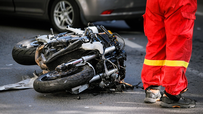 Crashed motorcycle after road accident with a car on a city street.
