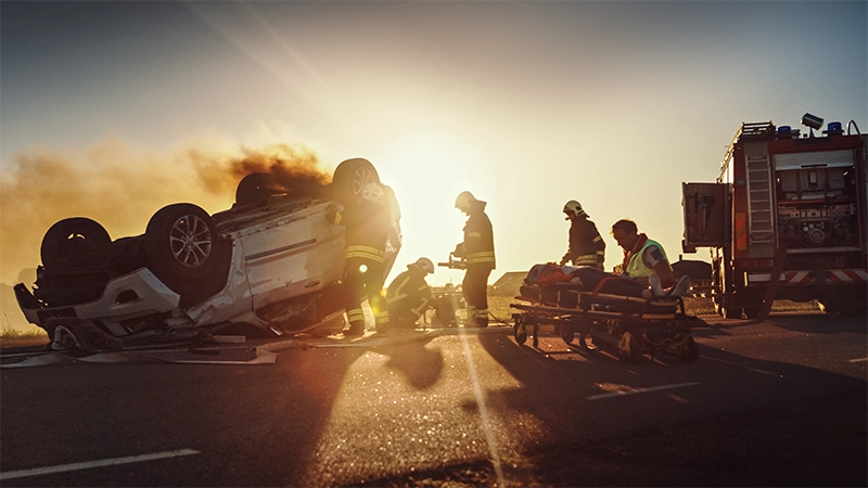 On the Car Crash Traffic Accident: Paramedics and Firefighters Rescue Injured Trapped Victims. Medics give First Aid to Female on Stretchers. Firemen Use Hydraulic Cutters Spreader to Open Vehicle.