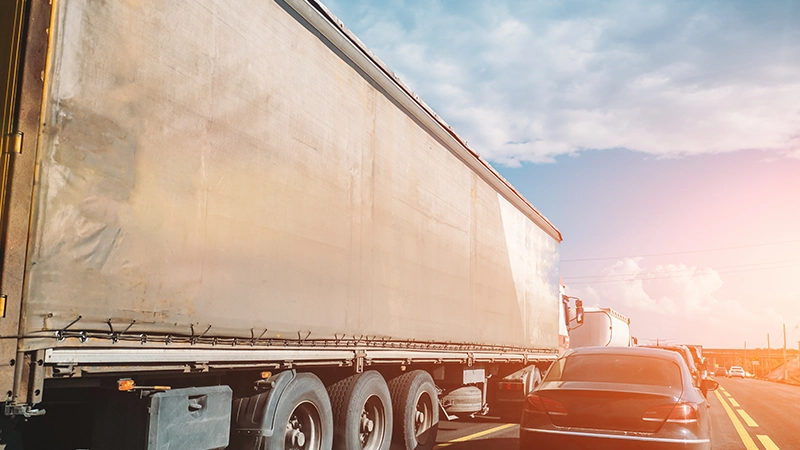 Truck transportation and cars on road or highway at sunset.