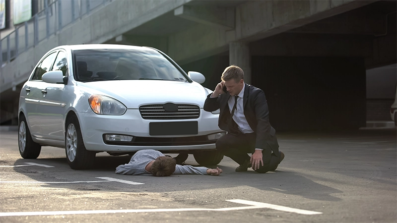 Nervous car driver calling ambulance, unconscious pedestrian hit by car.