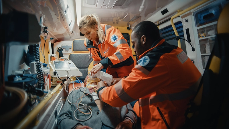Female and male ems paramedics provide medical help to an injured patient on the way to a healthcare hospital.