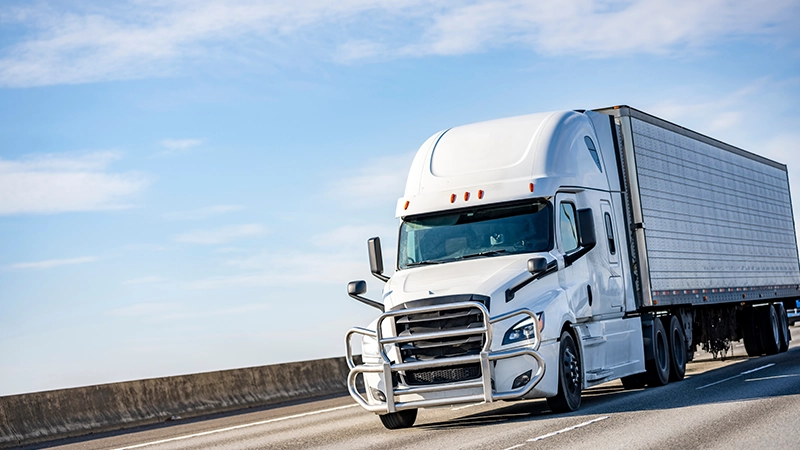 A modern, white semi-truck traveling on a highway.
