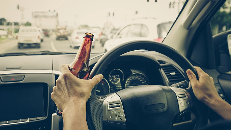 A driver holding alcoholic bottle while driving