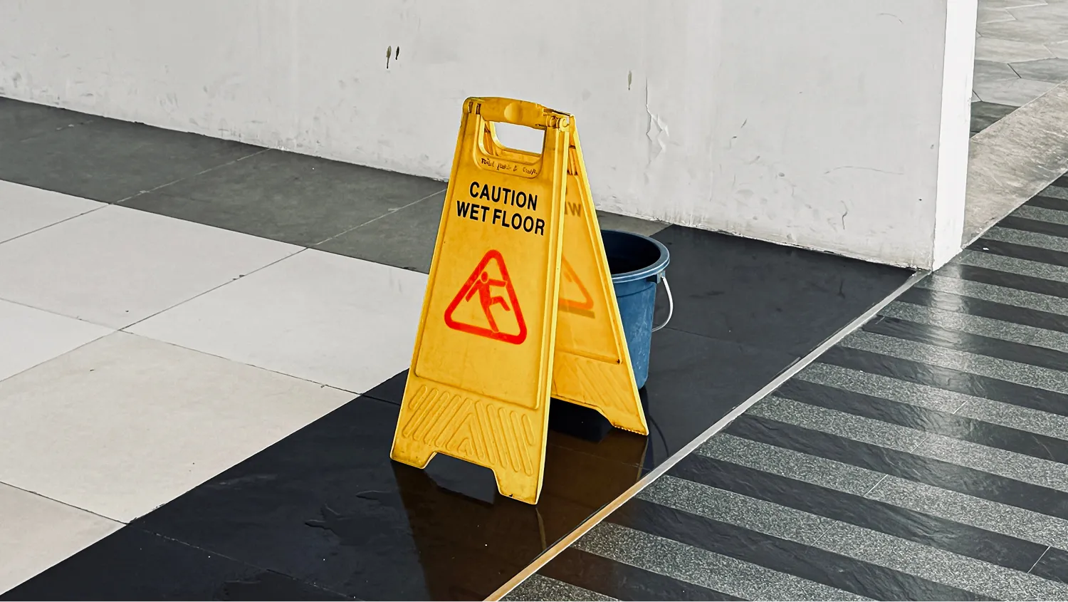 The sign is triangular and features a red pictogram of a person slipping.