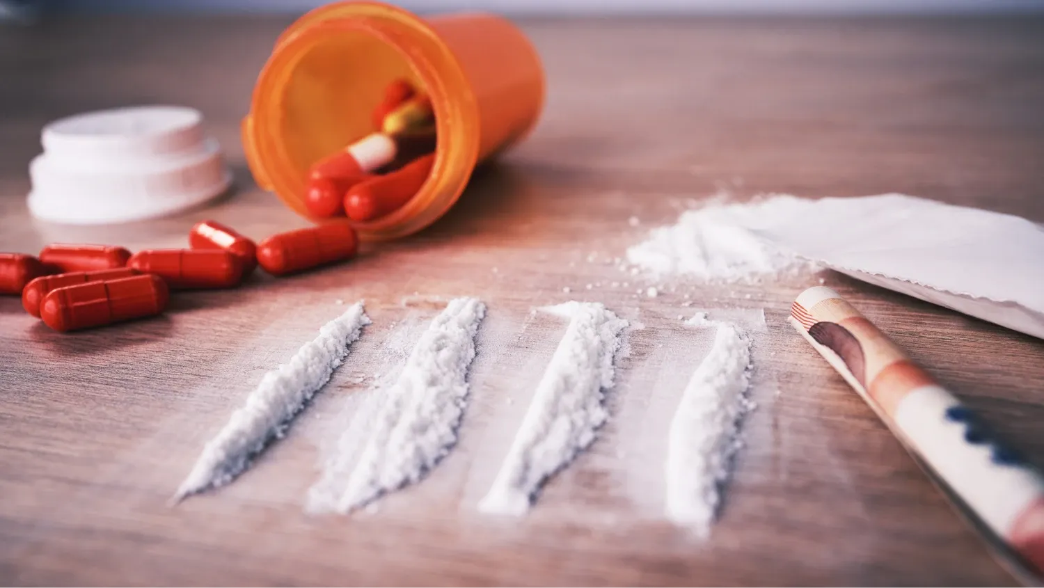 an array of illicit substances and drug paraphernalia on a wooden table.