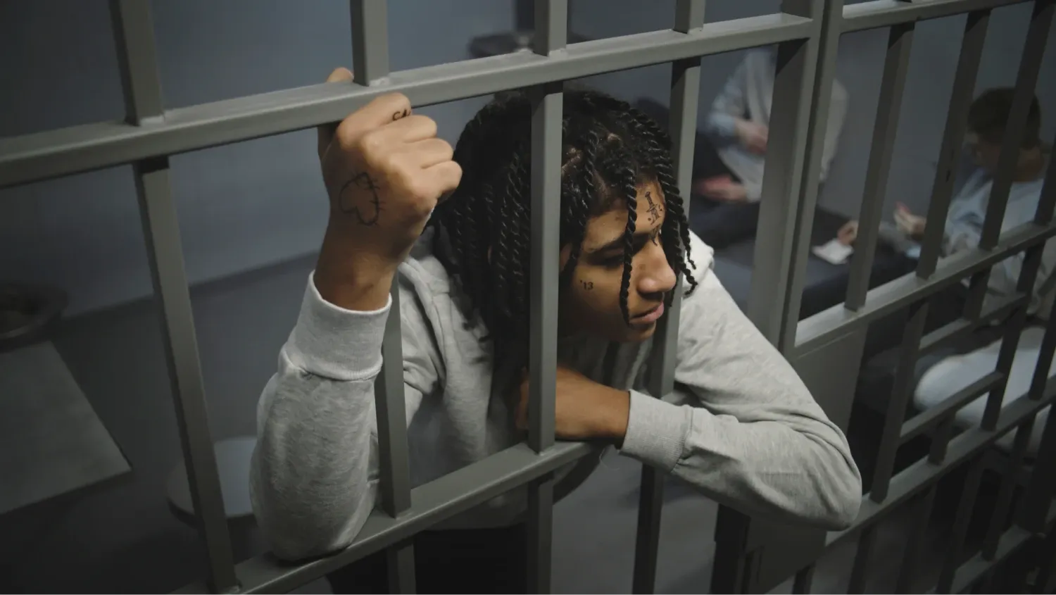 A young male with dreadlocks and face tattoos, possibly in a correctional facility or detention center.