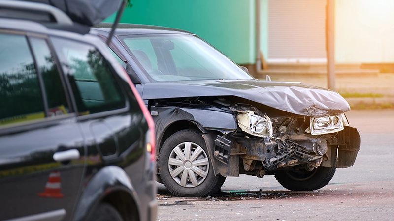 Damaged in car accident vehicle on city street crash site.